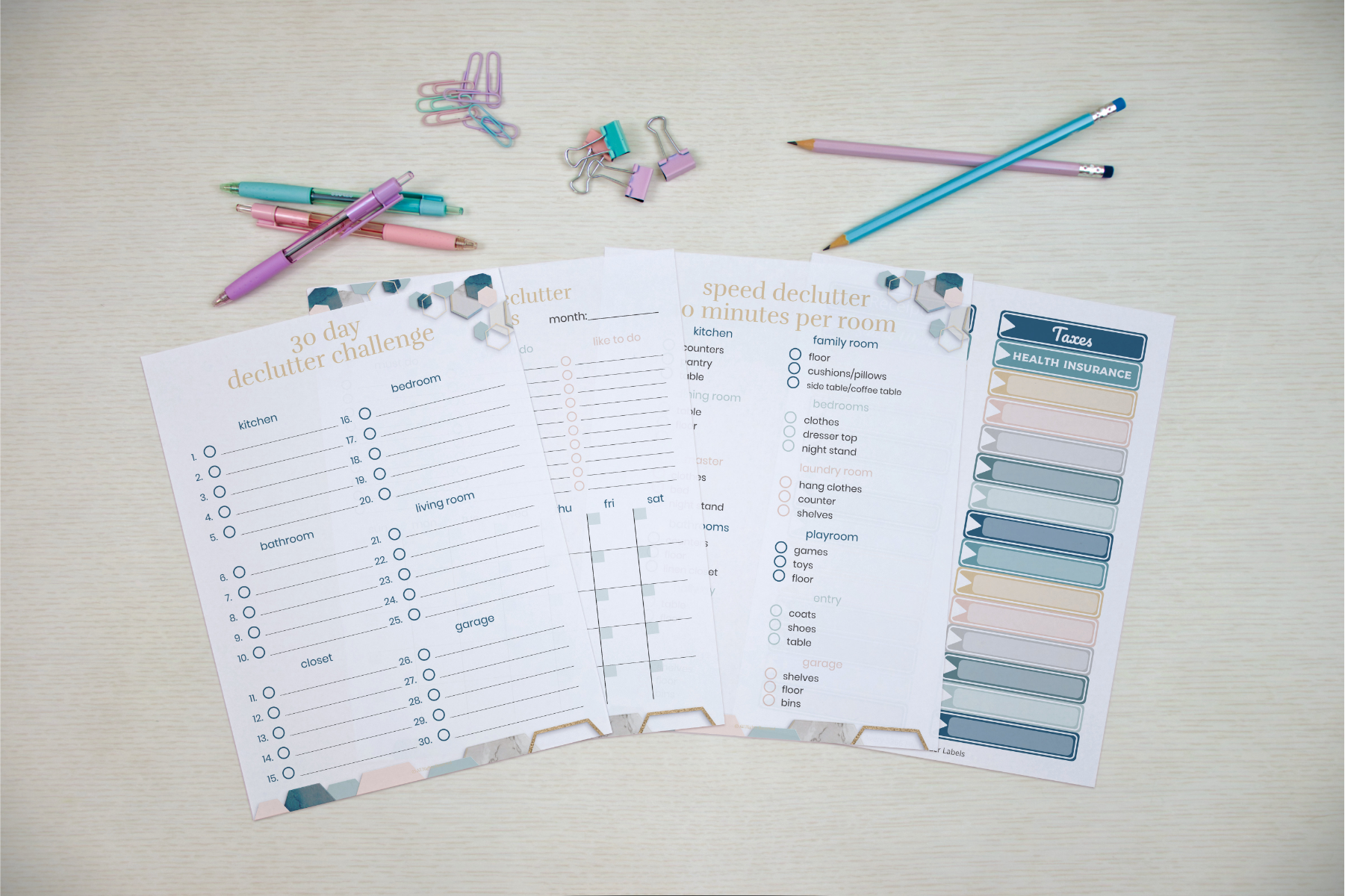 An overhead shot of decluttering and task planning worksheets, alongside Wondermom Shop's Declutter Binder: Your Guide to a Tidy and Stress-Free Home, pencils, and paper clips on a table.