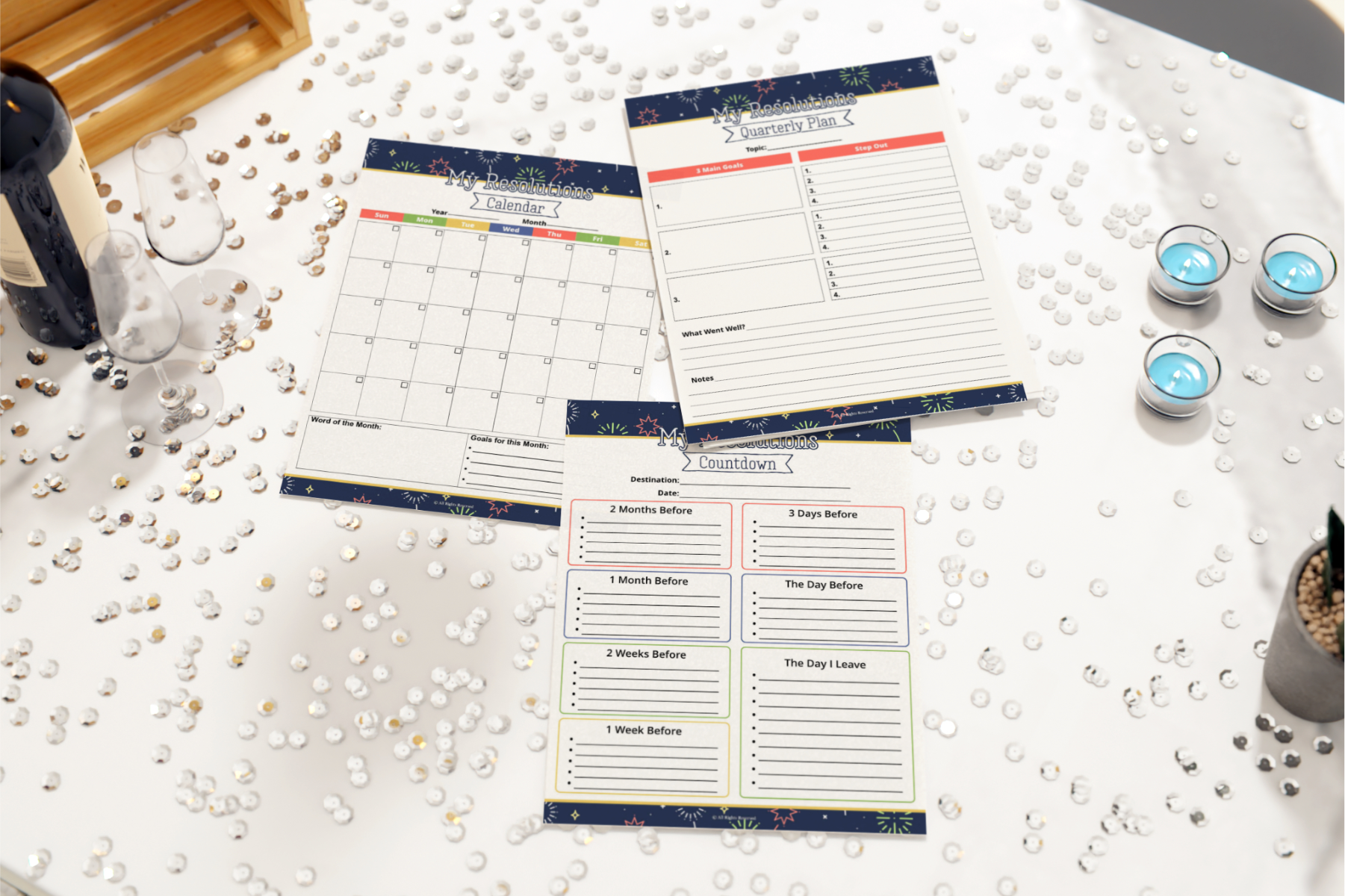 Three Resolution Planners by Wondermom Shop, ideal for goal-setting and personal growth, rest on a glittery table. Each planner includes a calendar, to-do lists, and timelines. Tealight candles and corked bottles gently accent the background.