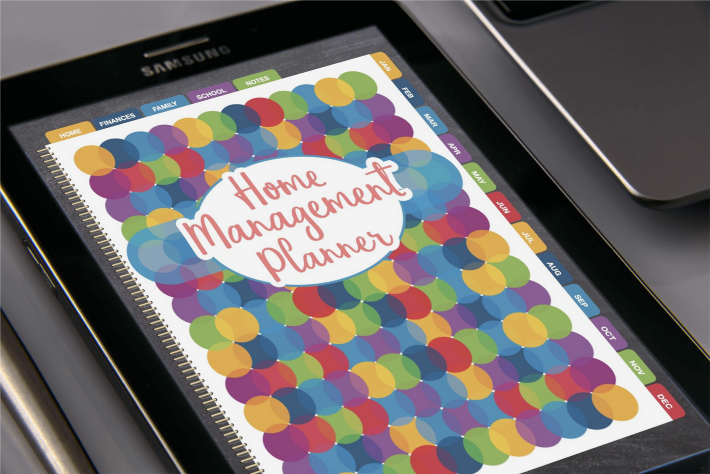 A digital Home Management Planner Bundle displayed on a Samsung tablet, featuring a colorful dotted cover design and including a Utilities Tracker by Wondermom Shop.