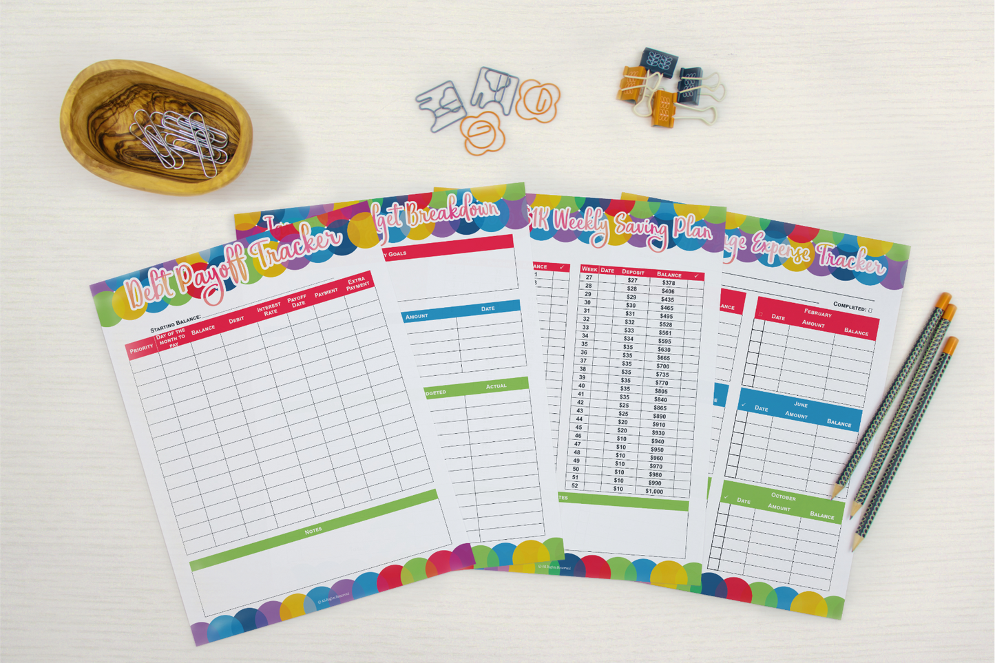 A set of colorful Wondermom Shop Budget Planners and pencils on a white table.