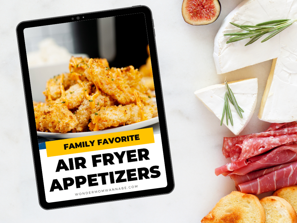 On a marble surface, a tablet displays Wondermom Shop's "Family Favorite Air Fryer Appetizers" digital cookbook, surrounded by cheese, figs, rosemary, cured meat, and bread—your go-to guide for crispy appetizers.
