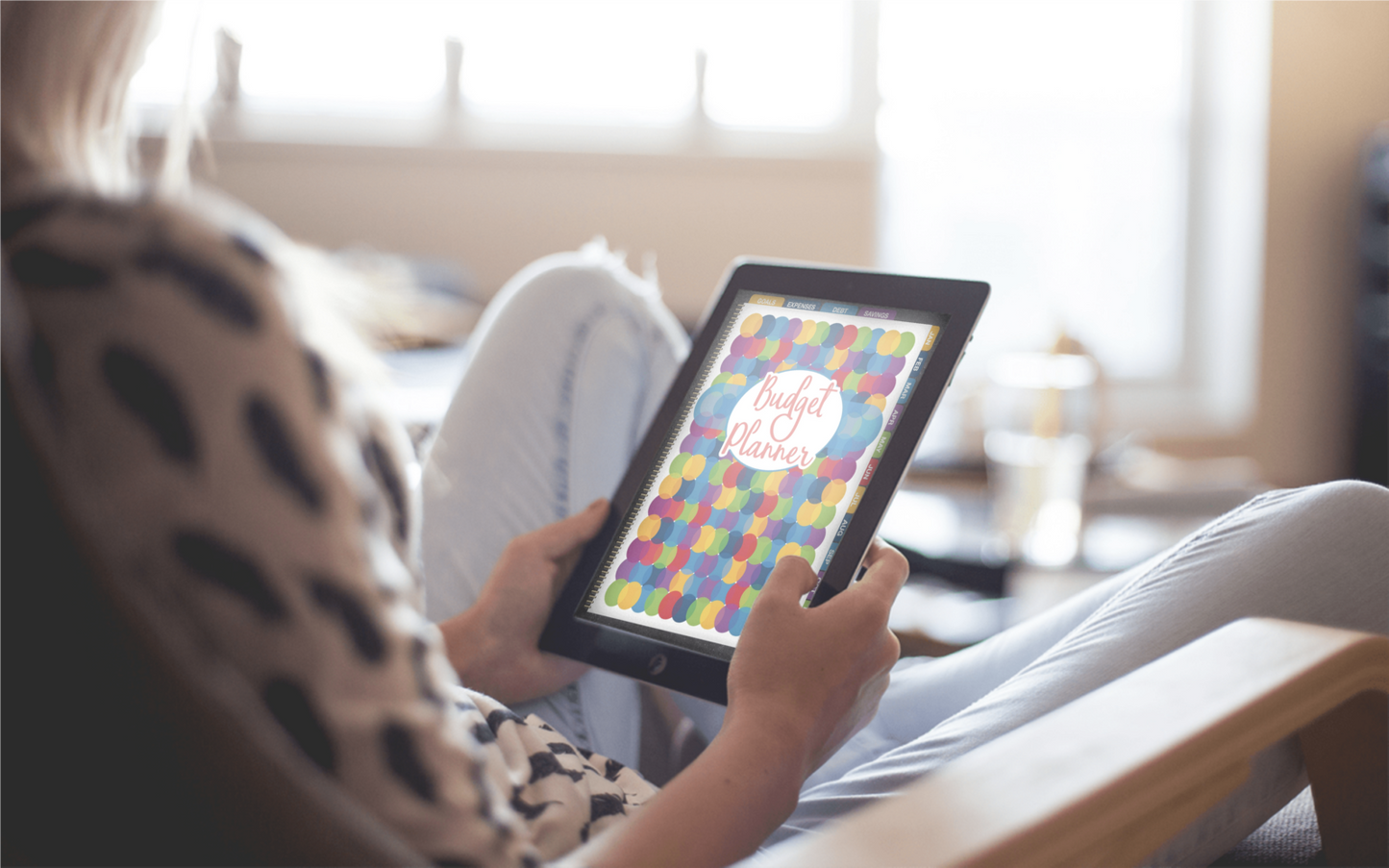 A woman sitting in a chair with a Wondermom Shop Digital Budget Planner in her hands.