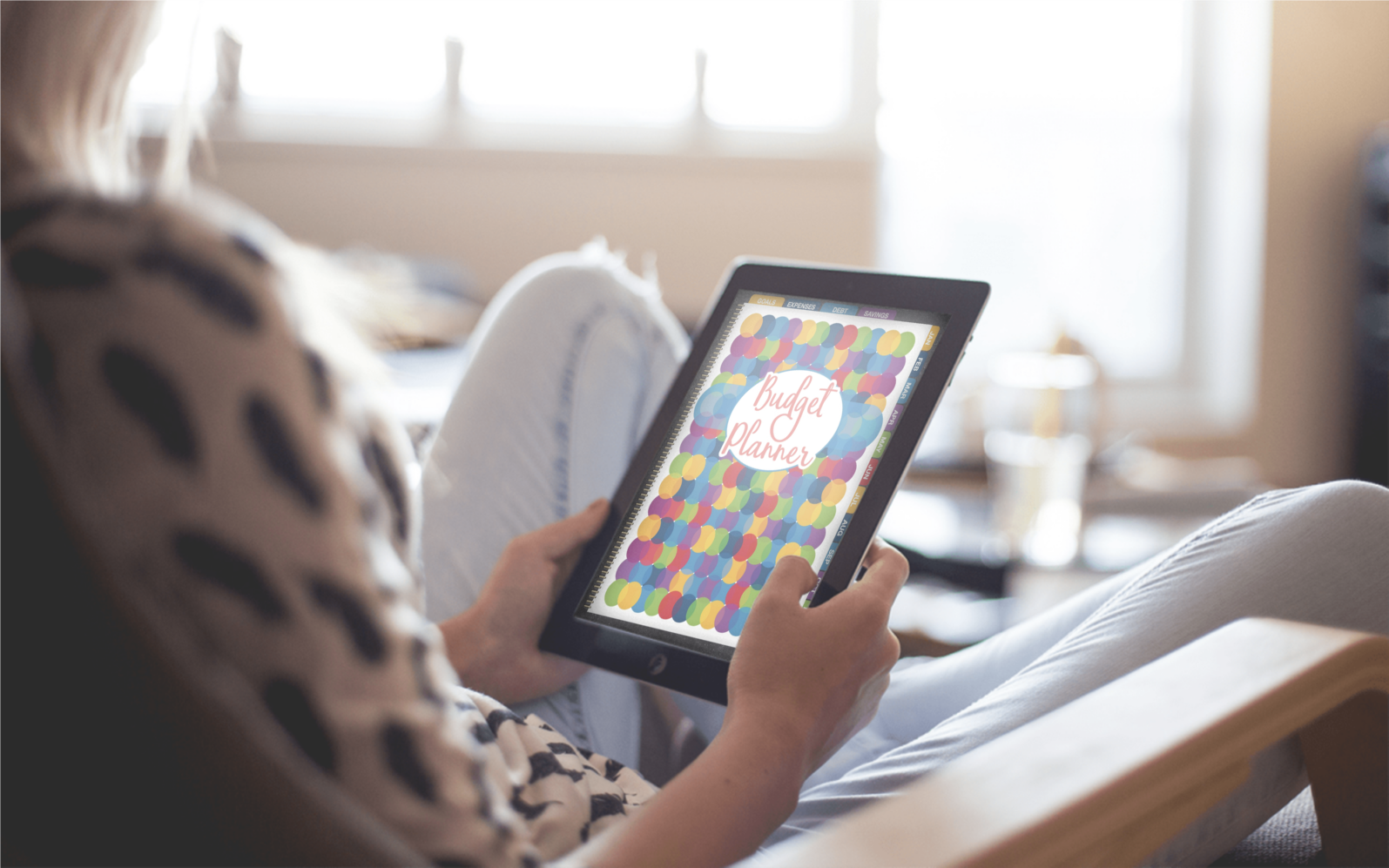 A woman sitting in a chair with a Wondermom Shop Digital Budget Planner in her hands.