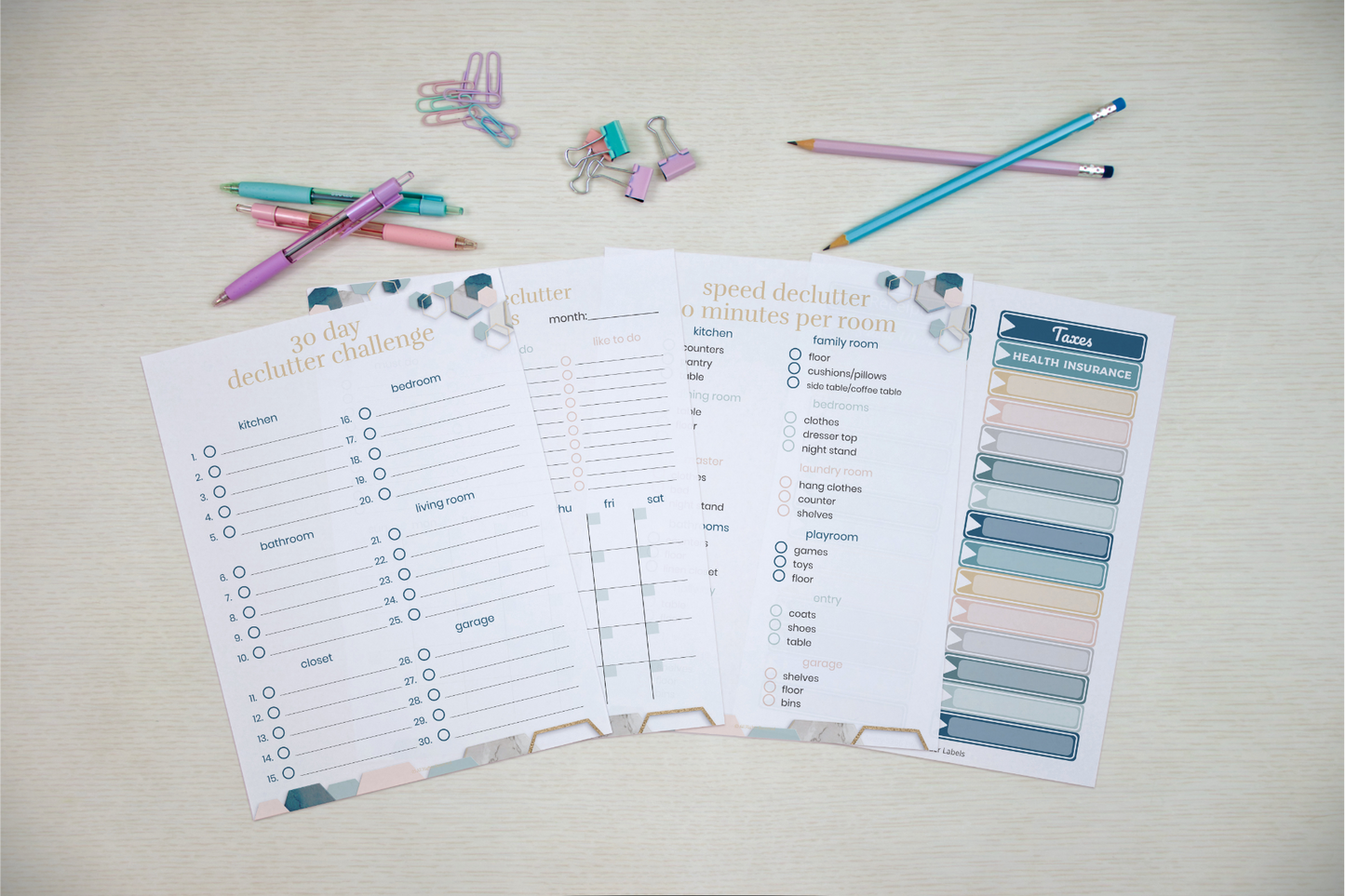An overhead shot of decluttering and task planning worksheets, alongside Wondermom Shop's Declutter Binder: Your Guide to a Tidy and Stress-Free Home, pencils, and paper clips on a table.