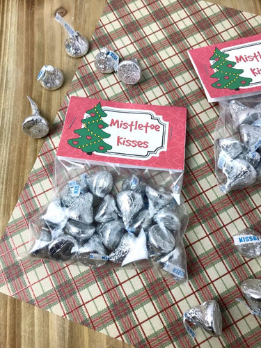 Two bags of VIP Vault Mistletoe Kisses Treat Bags with printable treat bag toppers on a table, perfect for the Christmas season.