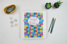 Load image into Gallery viewer, A colorful Budget Planner from Wondermom Shop with pens and pencils next to it.
