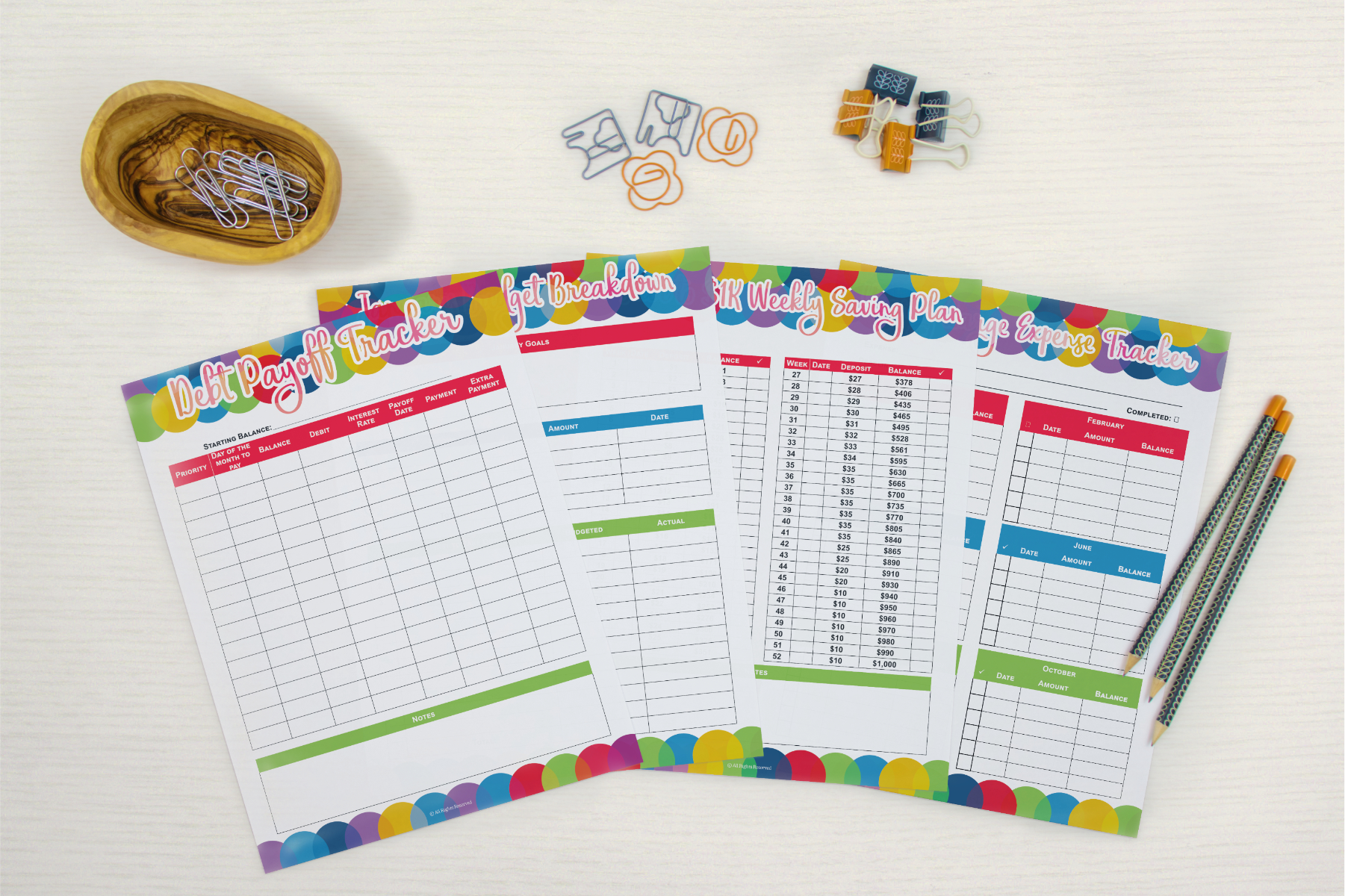 A set of colorful Wondermom Shop Budget Planners and pencils on a white table.